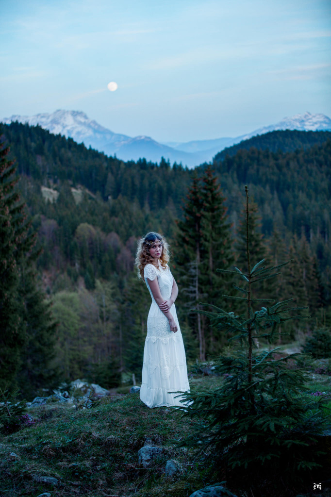 aufgehender Mond über den Bergen und dem Bergwald, Braut mit Brautkleid leicht Richtung Kamera gedreht, Blick in die Kamera, grandioses Brautkleid, blonde lange Locken, Portfolio, Wildromantisch, Brautkleid, Mode, Hochzeitsmode, Hochzeit, , Vintage Brautkleider, Styled Shoot, Wilder Kaiser, Vintage-Bohème, Hochzeitskleider, Ernst Merkhofer, Fotograf, Brautkleid Inspiration , Brautkleid, Spitze, Brautstrauss,