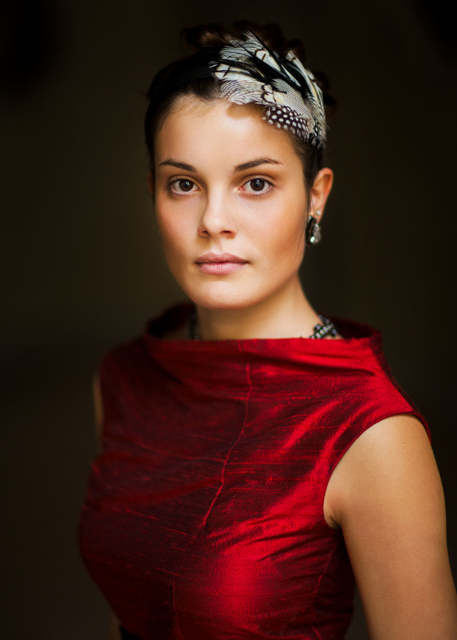 junge Frau in rotem Kleid und Haarschmuck schaut offen direkt in die Kamera, natürliches Fensterlicht mutet an wie gemalt. EMF Ernst Merkhofer Portraits, Portfolio,