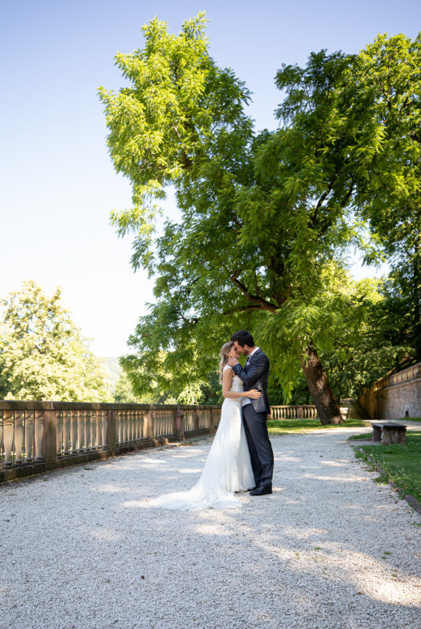 junges Brautpaar steht im Park mit großen Bäumen zärtlich umarmend bereit zum Kuss. After Wedding Session in Heidelberg Schloßpark