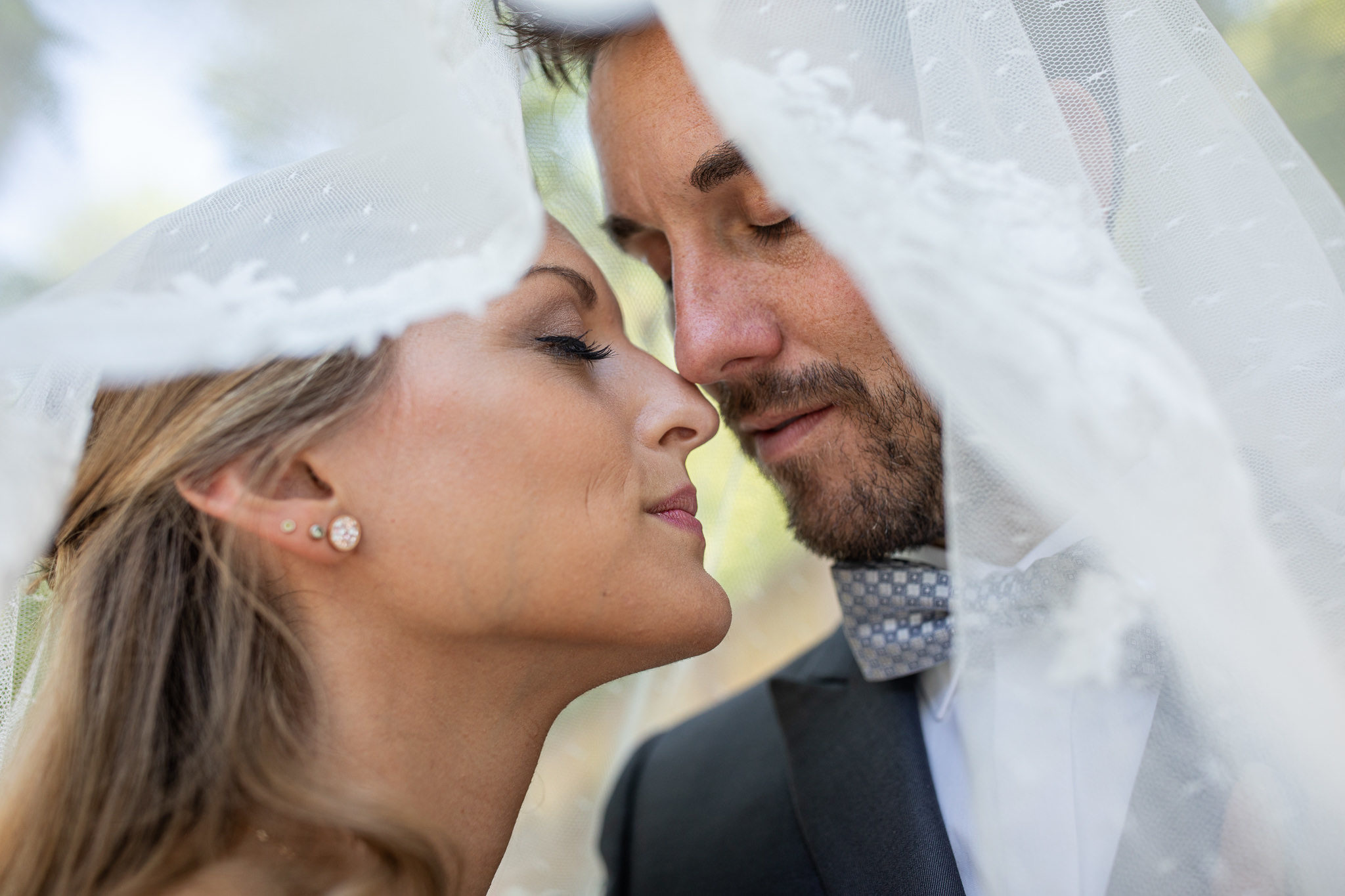 Romantik unter dem Schleier, das Brautpaar steht mit geschloßenen Augen eng beieinander, die Gesichter berühren sich fast. Den Schleier über sich gelegt genießen sie die Zweisamkeit. After Wedding in Heidelberg.