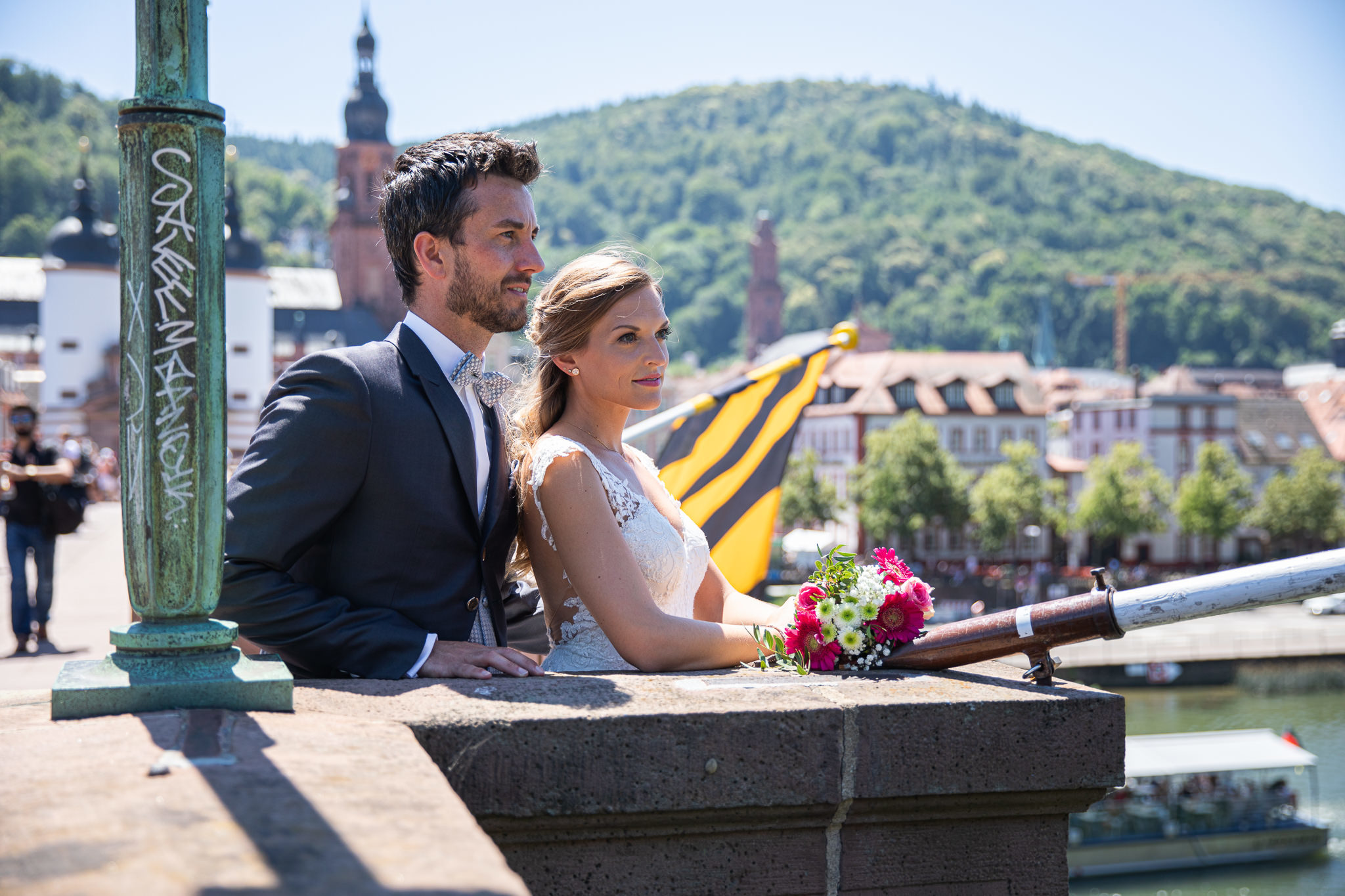 Brautpaar blickt von der Alten Brücke in Heidelberg auf den Neckar. Altstadt im Hintergrund. After Wedding Session.